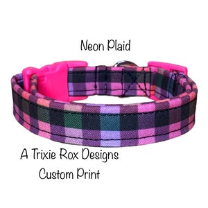 May include: A pink and black plaid dog collar with a pink plastic buckle. The collar is labeled "Neon Plaid" and "A Trixie Rox Designs Custom Print".