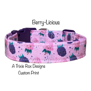 May include: A pink dog collar with a custom print of purple berries with faces. The collar has a purple buckle and the text "Berry-licious" and "A Trixie Rox Designs Custom Print" are printed on the collar.