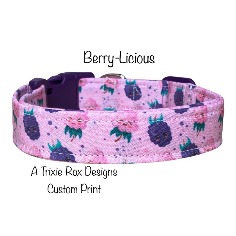 May include: A pink dog collar with a custom print of purple berries with faces. The collar has a purple buckle and the text "Berry-licious" and "A Trixie Rox Designs Custom Print" are printed on the collar.