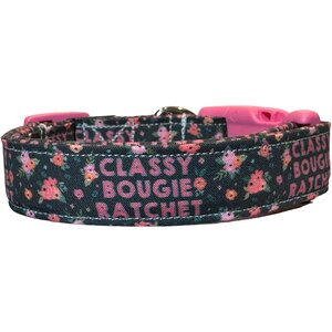 May include: A black dog collar with a pink floral print and the text "Classy Bougie Ratchet" in pink.