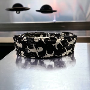 May include: Black dog collar with a white alien pattern. The collar is made of fabric and has a black buckle.