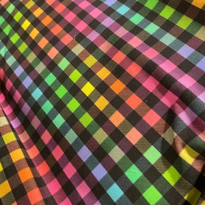 May include: A black and rainbow checkered fabric with a diagonal pattern. The fabric is made of a soft, smooth material.