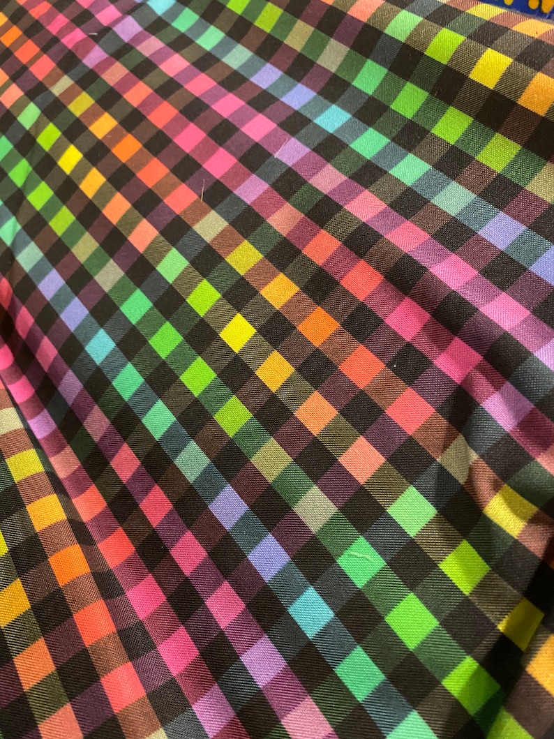 May include: A black and rainbow checkered fabric with a diagonal pattern. The fabric is made of a soft, smooth material.