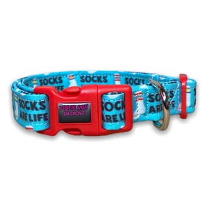 The light blue sock-patterned dog collar viewed from the front, showing a red plastic side-release buckle with a Trixie Rox Designs logo.