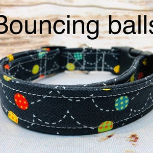 May include: A black dog collar with a white stitching pattern and colorful bouncing balls print. The collar has a black plastic buckle.