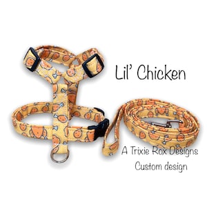 May include: A yellow and orange dog harness and leash set with a chicken leg print. The set is labeled "Lil' Chicken" and "A Trixie Rox Designs Custom design".