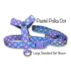 May include: A lavender dog harness and leash set with a pastel polka dot pattern. The harness has a plastic buckle and a metal D-ring. The leash is rolled up next to the harness. Text on the image reads "Pastel Polka Dot" and "Large Standard Set Shown."