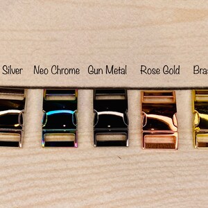 Peut inclure: Cinq fermoirs m&eacute;talliques dans diff&eacute;rentes finitions&nbsp;: argent, chrome n&eacute;o, m&eacute;tal gris, or rose et laiton. Les fermoirs sont dispos&eacute;s en rang&eacute;e sur une surface en bois brun clair.