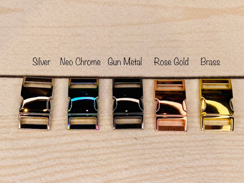 Peut inclure: Cinq fermoirs m&eacute;talliques dans diff&eacute;rentes finitions&nbsp;: argent, chrome n&eacute;o, m&eacute;tal gris, or rose et laiton. Les fermoirs sont dispos&eacute;s en rang&eacute;e sur une surface en bois brun clair.