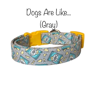 May include: Gray dog collar with a blue and white chip bag pattern. The collar has a yellow plastic buckle and the text "Dogs Are Like... (Gray)" is written above the collar.