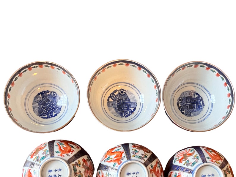 Puede incluir: Colecci&oacute;n de seis cuencos de cer&aacute;mica antiguos. Los cuencos tienen un interior blanco con un dise&ntilde;o azul y blanco en el centro. Los bordes est&aacute;n decorados con un patr&oacute;n floral rojo y azul. La parte inferior de los cuencos tiene un dise&ntilde;o de drag&oacute;n rojo y naranja.