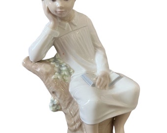 Porcelain Lladro boy sitting on a stump reading a book figurine.  