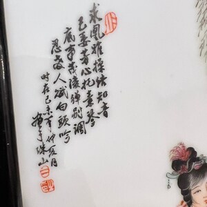 Puede incluir: Un plato de porcelana blanca con caligraf&iacute;a negra en caracteres chinos. Los caracteres est&aacute;n escritos en una escritura fluida y est&aacute;n dispuestos en una columna vertical. El plato est&aacute; decorado con un sello rojo en la parte inferior.