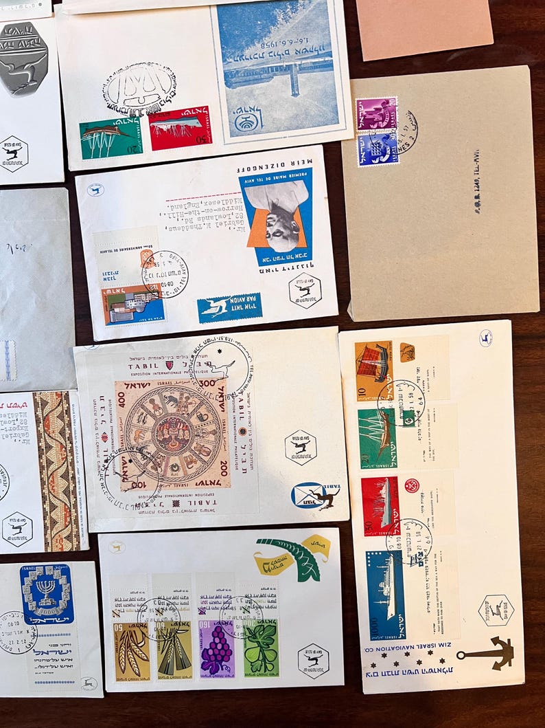 以下が含まれることがあります： 様々なデザインと色を持つ、ヴィンテージの封筒と切手のコレクション。封筒には、建物、肖像画、シンボルの画像が描かれた切手が貼られています。一部の封筒にはヘブライ語と英語のテキストがあり、郵便マークと日付が記載されています。