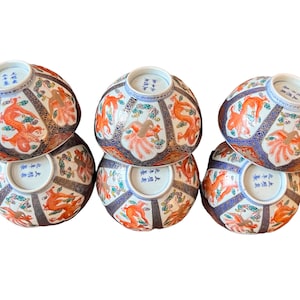 Puede incluir: Seis cuencos de cer&aacute;mica decorativos con dise&ntilde;os intrincados. Cada cuenco presenta un vibrante motivo de drag&oacute;n naranja, complementado con detalles en azul, dorado y blanco. Los cuencos est&aacute;n dispuestos en una configuraci&oacute;n apilada, mostrando su detallada artesan&iacute;a y estilo art&iacute;stico.