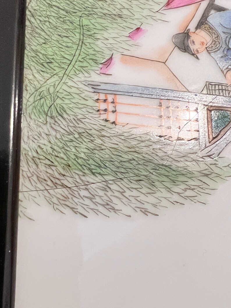 Puede incluir: Una pintura enmarcada vintage que representa una escena de una persona con una t&uacute;nica azul y blanca de pie frente a un edificio con un techo verde. La pintura est&aacute; sobre un fondo de follaje verde.