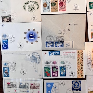 以下が含まれることがあります： 様々なデザインと色を持つ、ヴィンテージの封筒と切手のコレクション。封筒には、花柄、地図、歴史的シンボルなど、ヘブライ語のテキストと画像が印刷された切手が貼られています。一部の封筒には消印と手書きのメモがあります。