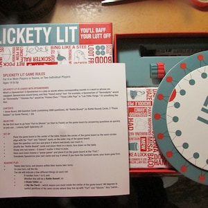 Puede incluir: Juego de mesa "Splickety Lit" con un diseño en verde azulado y rojo. El juego incluye una ruleta, cartas y un tablero. La caja presenta el texto "You'll Baff Your Lutt Off".