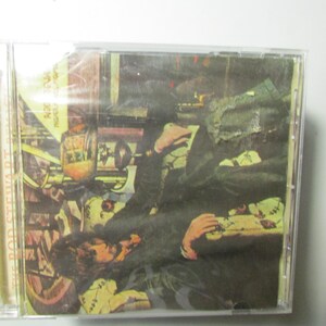 May include: A CD case featuring the album cover of Rod Stewart's album. The artwork depicts a man lying down with a dark green jacket and a yellow shirt. The background includes a motorcycle and other objects.