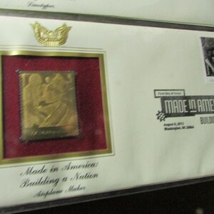 May include: A gold-colored stamp with an image of two figures, set within a red frame and a gold border. The stamp is part of a "Made in America: Building a Nation" series, with text on the envelope. The envelope also features a small stamp and an eagle emblem.