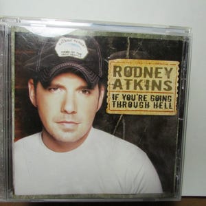 May include: CD case featuring Rodney Atkins with the album title "If You're Going Through Hell." Atkins is wearing a baseball cap and a white t-shirt. The album cover has a rustic, weathered appearance.