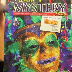 May include: A board game box titled "Murder Mystery Party" with a Mardi Gras theme. The box features a glittery gold mask with green and purple accents. Text on the box includes "Dinner Party Game for 8 Players" and "Murder at Mardi Gras."