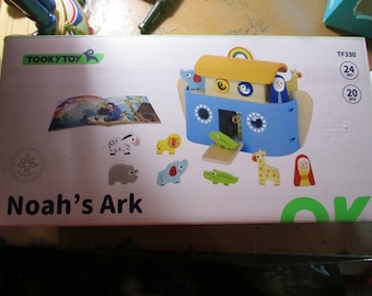 May include: A boxed wooden Noah's Ark toy set. The blue ark has a yellow roof and porthole windows. The set includes animal figures like a zebra, lion, elephant, and giraffe. The box reads "Noah's Ark" and "TOOKYTOY".