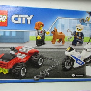 May include: LEGO City set featuring a red off-road vehicle, a white and blue police motorcycle, and three minifigures. The set includes a brown dog figure and a tow chain. The box has the LEGO City logo and the number 60139.