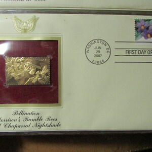 May include: A commemorative envelope featuring a gold-colored stamp with a bee and floral design. The stamp is set against a burgundy background within a frame. The envelope is stamped "First Day of Issue" with a Washington D.C. postmark.