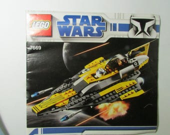 May include: LEGO Star Wars set 7669 box art. The image shows a yellow, gray, and black spaceship with a pilot in the cockpit. The background depicts a space scene with a planet and laser fire.