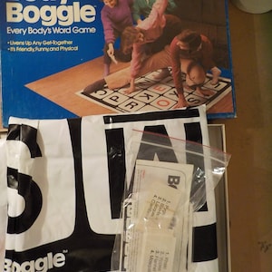 May include: A vintage Parker Brothers Body Boggle board game box with the game's title in white and blue. The box features a graphic of people playing the game. The game includes a Boggle bag and game pieces.