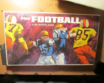 May include: A vintage board game box titled "PRO FOOTBALL" with a 3M Sports Game logo. The box art features illustrations of football players in action, wearing yellow, blue, and orange uniforms. The background is a mix of red and purple.