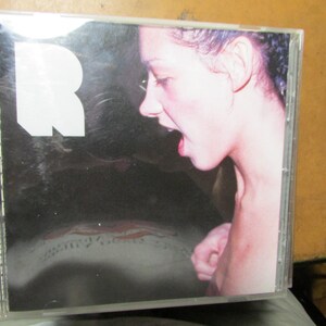 May include: A clear plastic CD jewel case featuring a cover with a large white letter R on a black background. The artwork includes a profile photograph of a person with their mouth open, and the word RESPECT is printed vertically in white text.