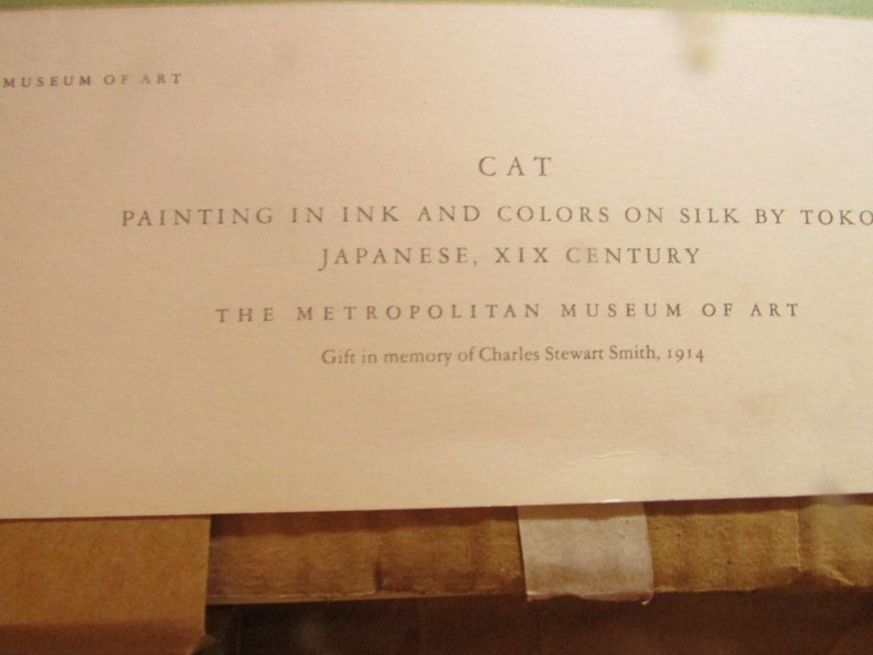 May include: A close-up of a printed document from The Metropolitan Museum of Art. The text reads "CAT, Painting in ink and colors on silk by Toko, Japanese, XIX Century." The document is a gift in memory of Charles Stewart Smith, 1914.