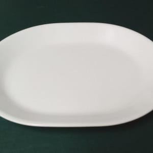 May include: A plain, solid white oval-shaped serving platter with a smooth, glossy finish and a slightly raised rim. The dish features a simple, clean design with no patterns, textures, or decorative elements, presenting a uniform white surface.