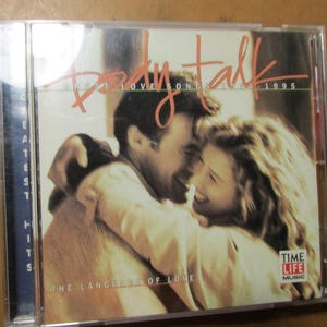 May include: A Body Talk Greatest Love Songs 1985-1995 music CD in a clear plastic jewel case. The cover features a photograph of a couple embracing, with the text Body Talk, The Language of Love, and the Time Life Music logo printed on the front.