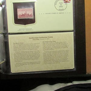 May include: A Smithsonian Institution stamp from August 10, 1946, displayed in a black album. The stamp features a pink image of a building. The album page also includes text about the stamp's history and subject.