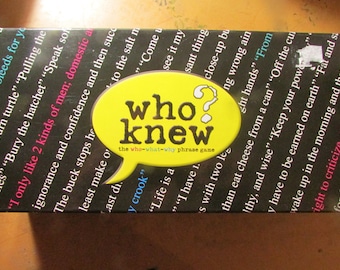 May include: A black game box with the title "who knew" in a yellow speech bubble. The box is covered in phrases like "Bury the hatchet" and "Life is a crook".