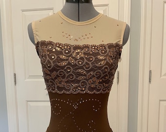 May include: A brown figure skating dress with a lace bodice and a sheer mesh overlay. The bodice is decorated with rhinestones and sequins. The skirt is a simple A-line shape.