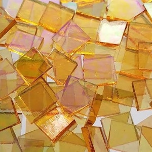 May include: A pile of iridescent gold glass tiles. The tiles are square and have a slightly textured surface. They are perfect for crafting and mosaic projects.