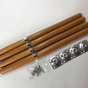 May include: Set of four wooden table legs with metal mounting plates and screws. The legs are a light brown colour and the plates are silver.