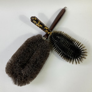Könnte beinhalten: Zwei vintage Bürsten mit braunem Griff und schwarzen Borsten. Eine Bürste hat einen Griff mit Schildpattmuster und die andere einen schlichten braunen Griff.