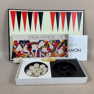 Puede incluir: Un juego de backgammon vintage con un tablero rojo, negro y blanco, piezas de madera y un libro de reglas. La caja presenta una ilustración colorida de cartas de juego con reyes y reinas.