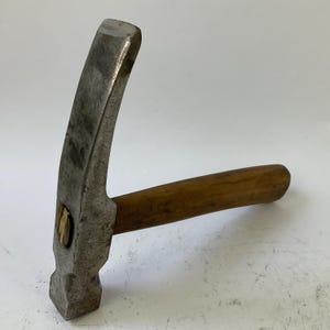 May include: A claw hammer with a wooden handle and a metal head. The hammer head is curved and has a claw on one side. The handle is made of wood and is a light brown color. The hammer is designed for construction and repair work.