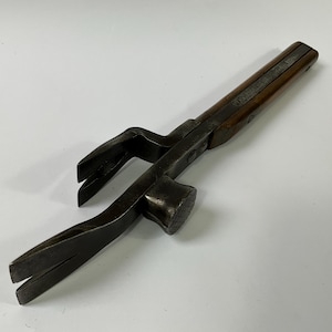 May include: A vintage claw hammer with a dark wooden handle and a metal head. The hammer features a claw for removing nails and a flat striking surface. The tool is designed for carpentry and construction tasks.