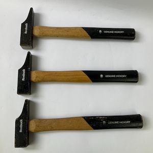 May include: Three claw hammers with wooden handles and black heads. The handles are two-toned, with a natural wood color and a black grip. The text "Roebuck" is printed on the hammer head, and "GENUINE HICKORY" is printed on the handle.