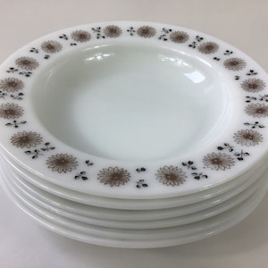 Puede incluir: Un conjunto de cinco tazones de sopa de cerámica blanca con un patrón floral marrón y negro alrededor del borde.