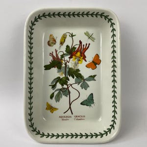 Puede incluir: Bandeja rectangular de cerámica blanca con una ilustración botánica de flores y mariposas. La bandeja tiene un borde de hojas verdes y el texto "AQUILEGIA GRACILIS Slender Columbine".