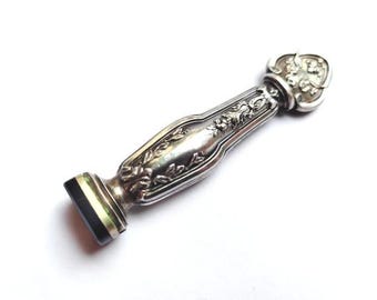 May include: Silver seal with an ornate design and a black and green stone seal.