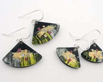 May include: A set of three black and silver earrings with a fan-shaped design. The earrings feature a black background with gold and red accents.